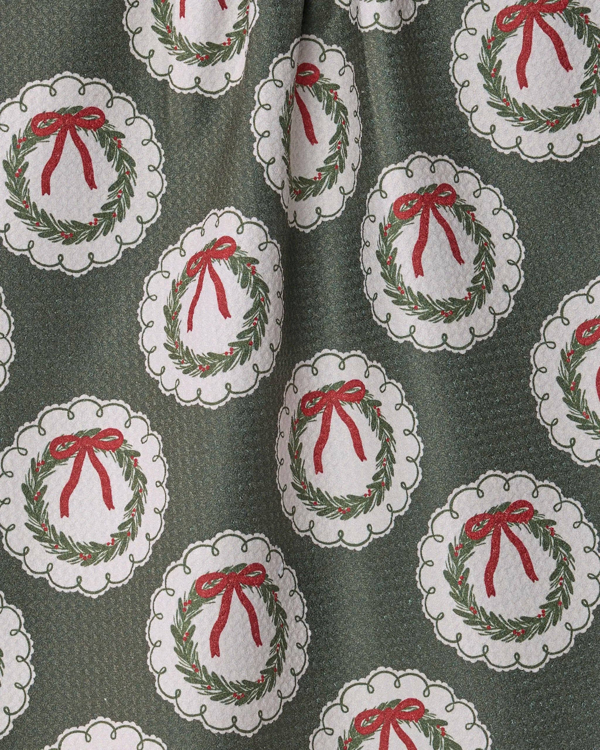 Close-up tea towel fabric with wreath ornament pattern, gray-green and red bows