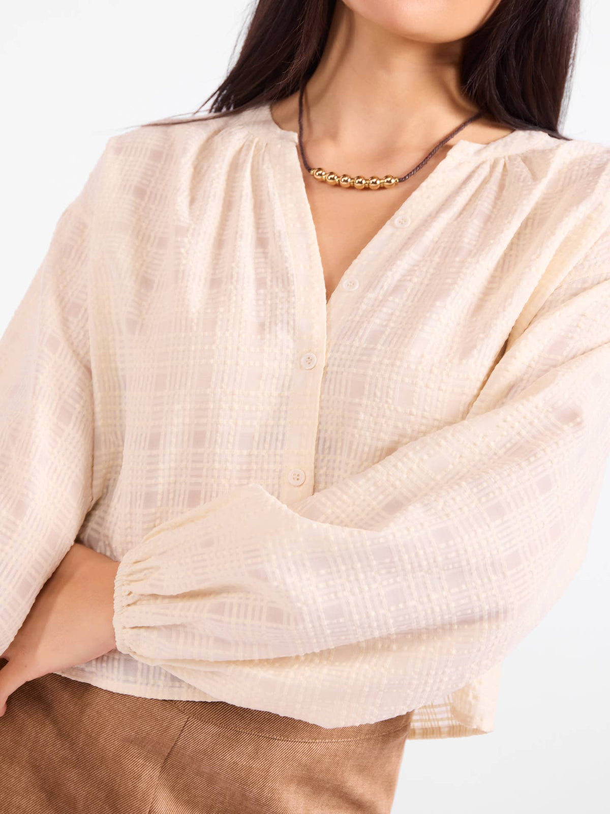 Light beige gauze blouse detail, button placket and draped sleeves