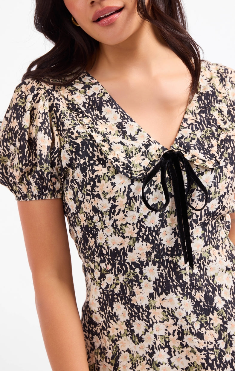 Close-up of floral mini dress neckline with tie bow and short puff sleeves