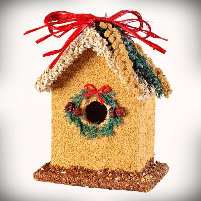 Yellow birdhouse decoration with wreath window and red ribbon garland