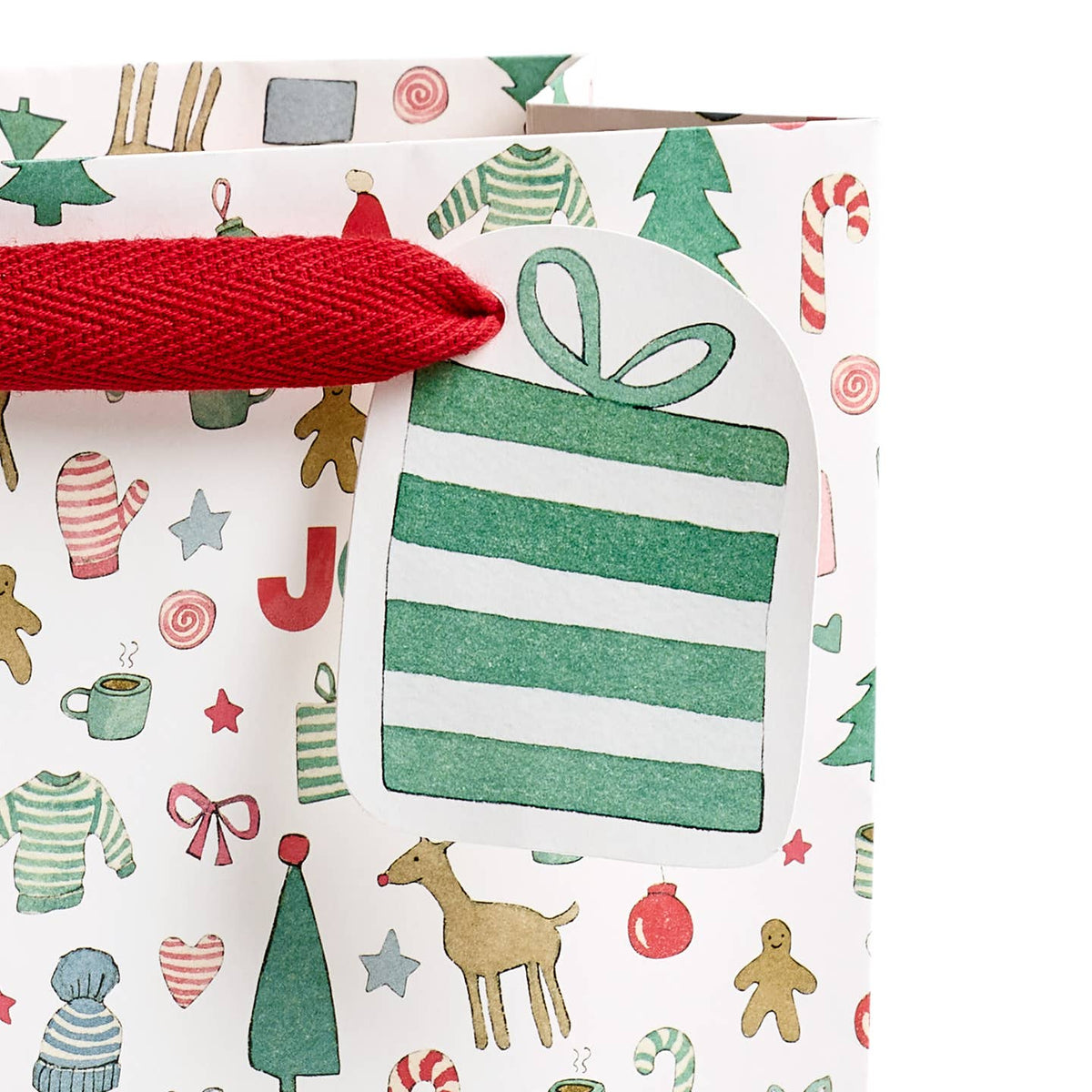 Holiday gift bag close-up: red rope handle and green striped gift tag on festive pattern