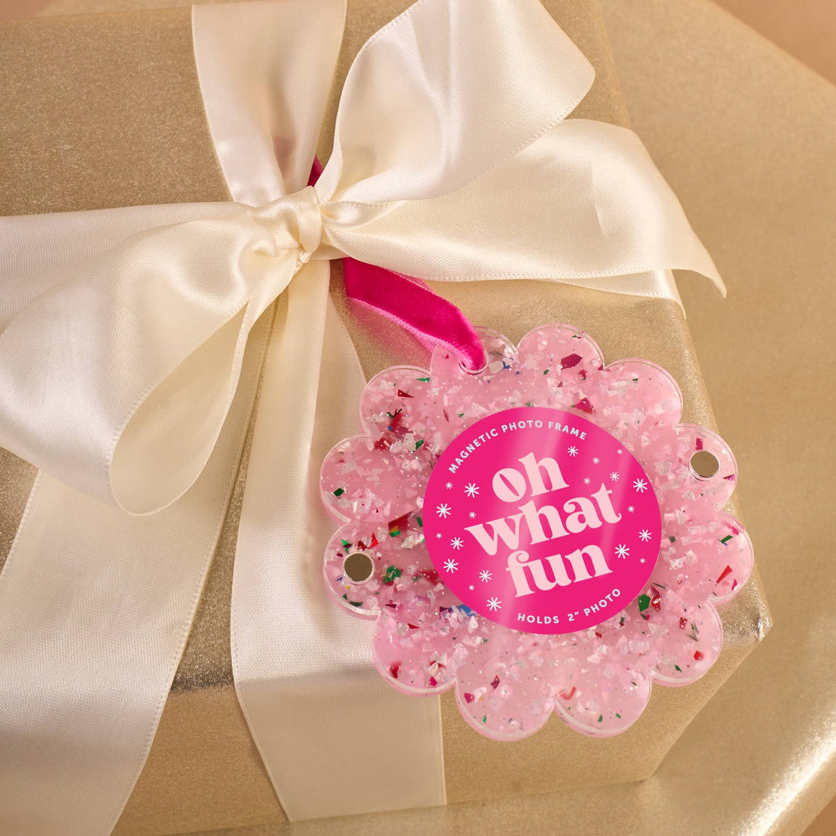 Pink scalloped confetti photo frame ornament with 'Oh what fun' on a gift with bow