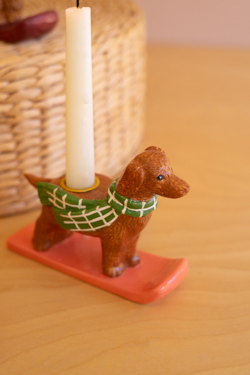 Ceramic dog taper candle holder with green scarf, candle on orange-red base