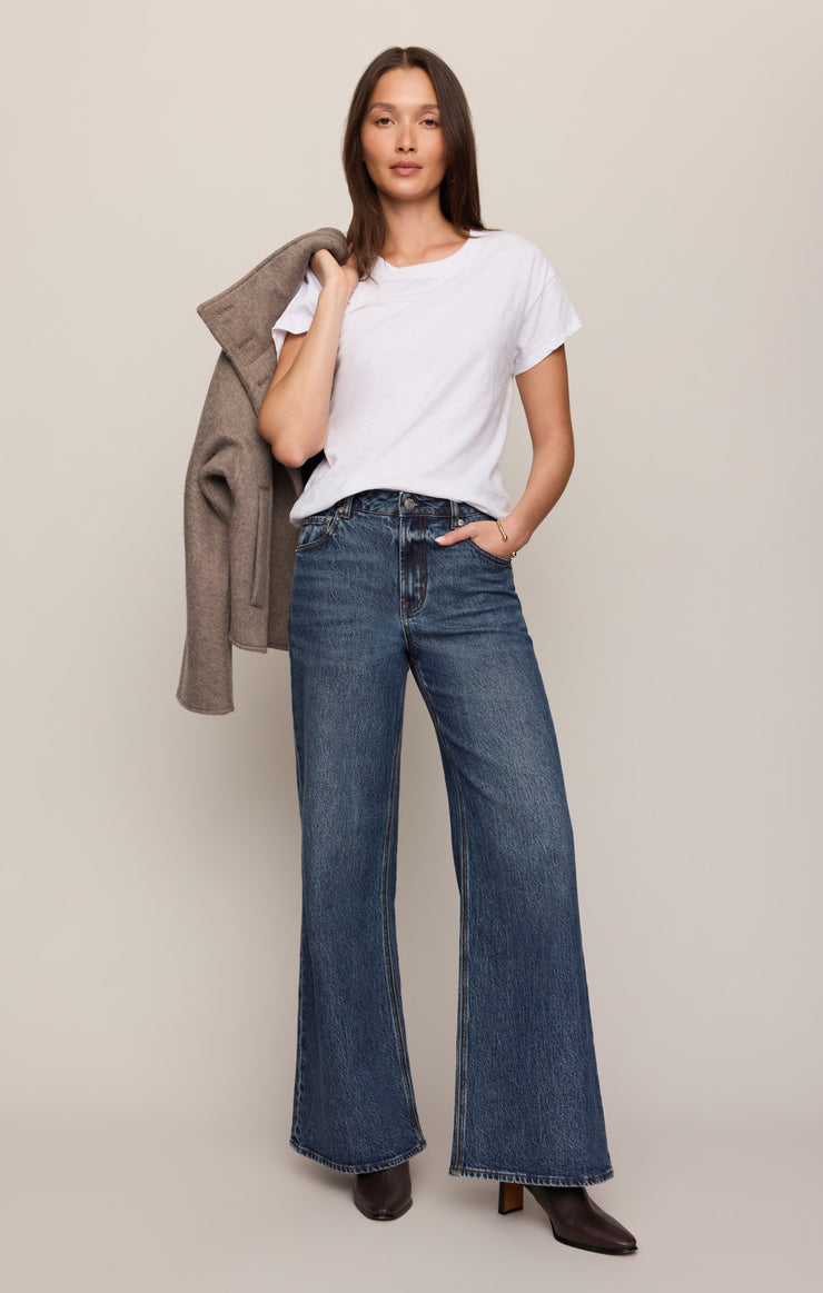Women's mid-rise wide-leg jeans in dark blue, front crease seams, button fly, flared hem.
