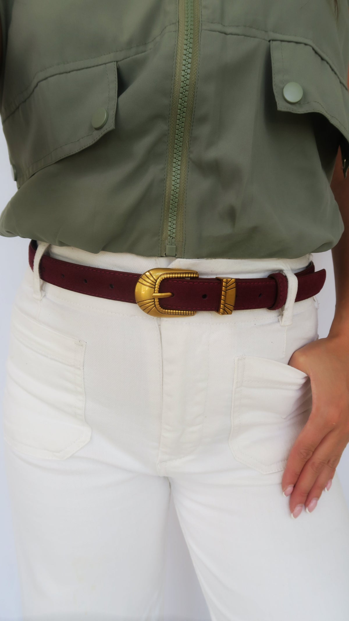 Burgundy belt with gold-tone oval buckle worn at waist over white jeans