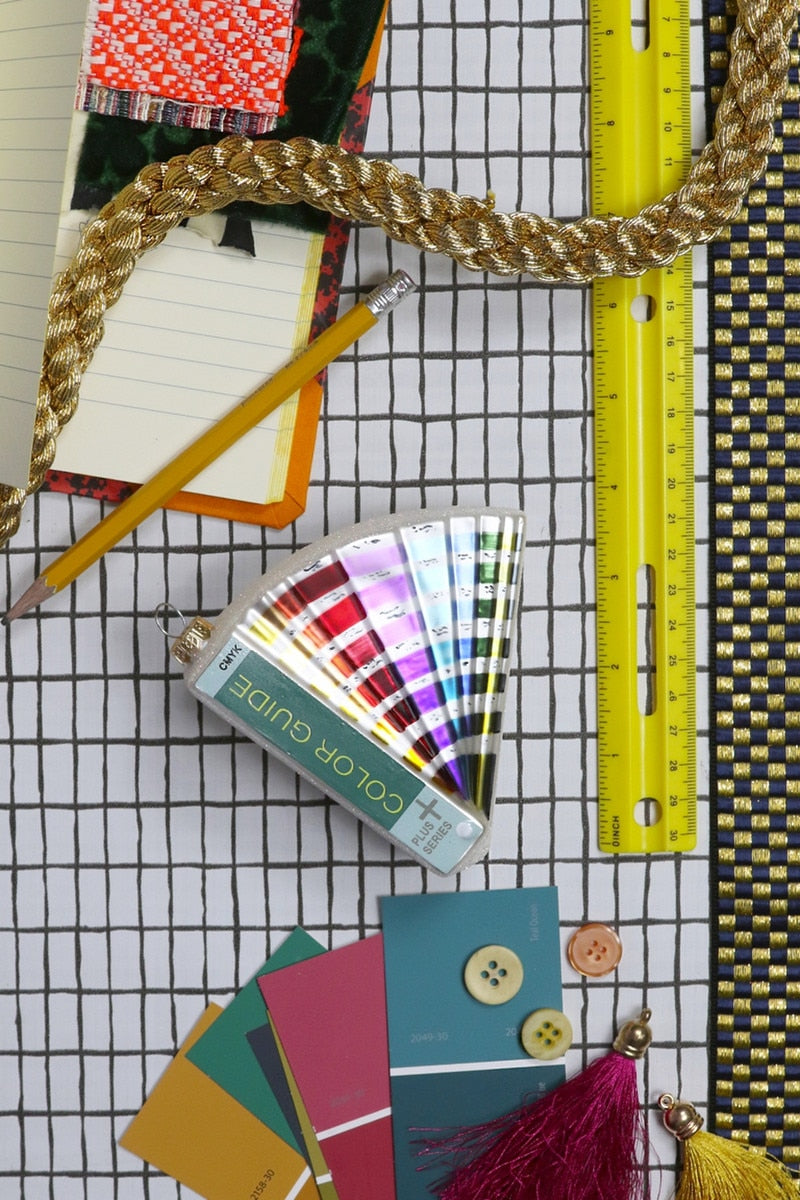 Triangular color guide ornament with multicolor stripes, tied gold string and tassel