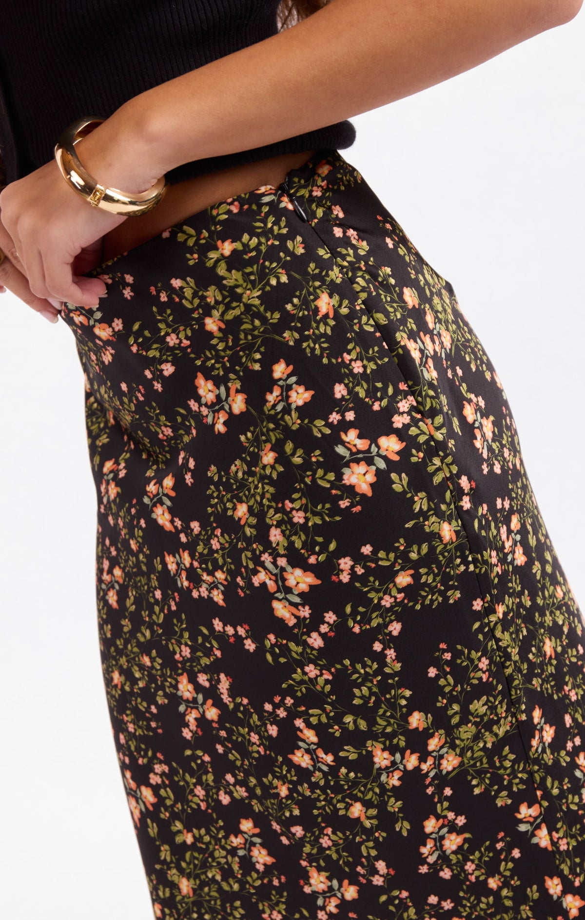 Floral midi skirt fabric close-up, dark base with orange, yellow, and green flower print