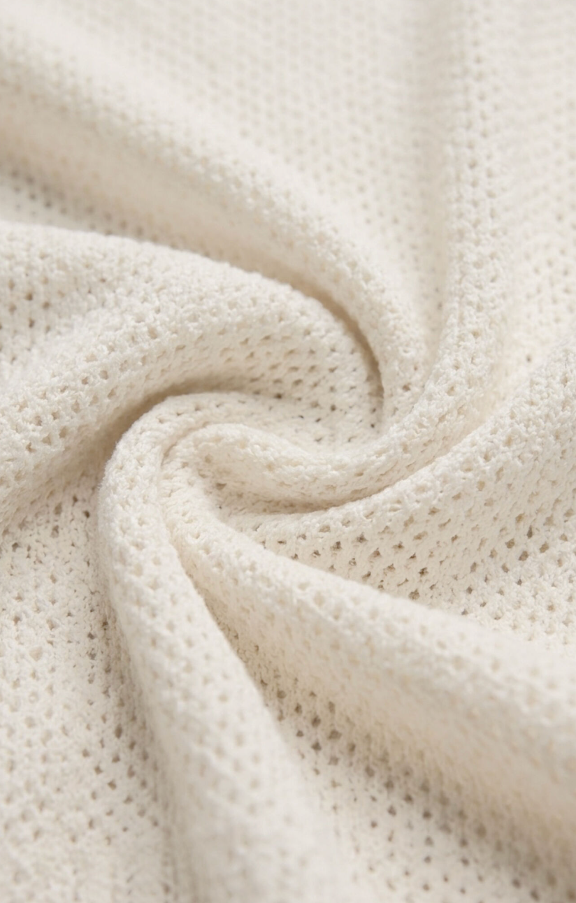 Close-up of cream crochet knit fabric with textured swirling stitch pattern