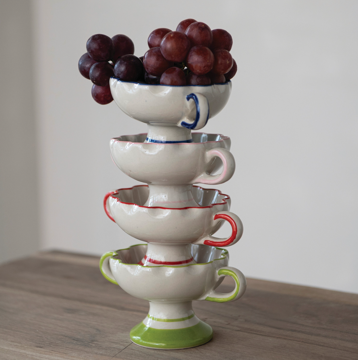 Stacked scalloped footed bowls, white ceramic with red, blue, and green accents and handles