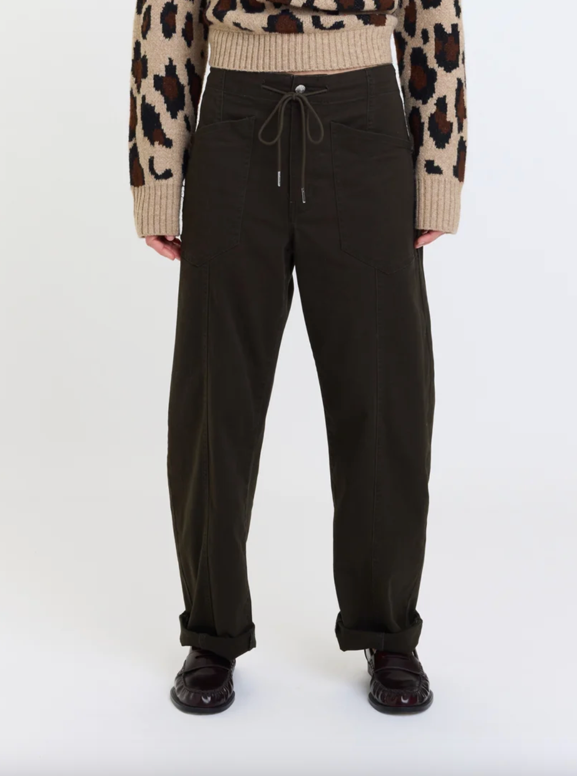 Close-up of drawstring barrel pants: black waist tie, front pockets, cuffed hem