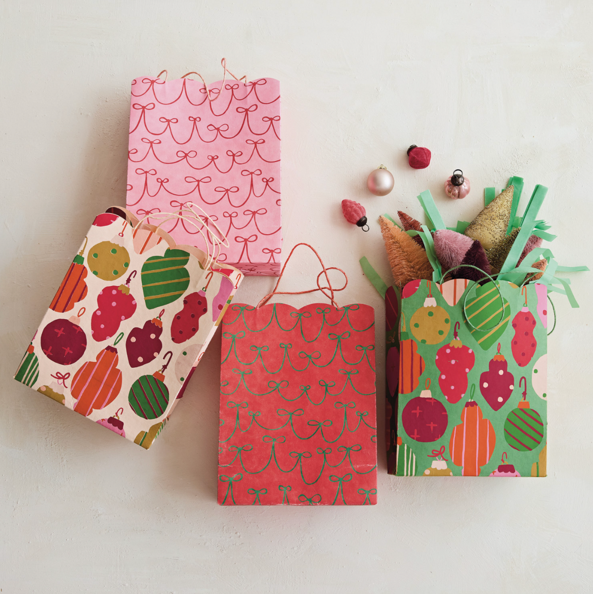 Scalloped holiday gift bags: pink and red scalloped fronts, plus green fruit pattern bag.
