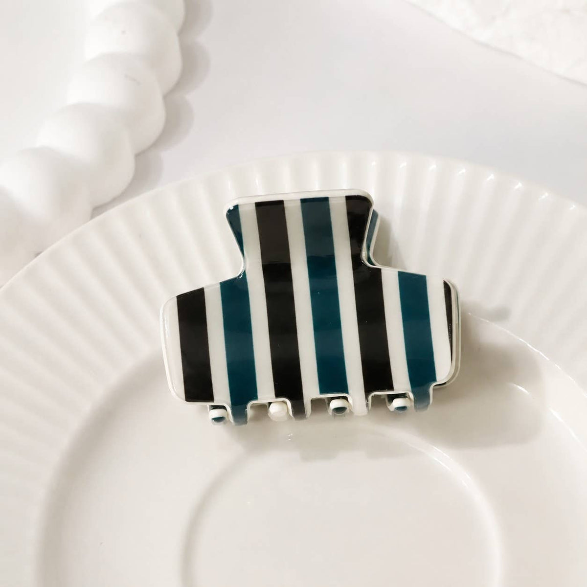 Striped hair claw clip with black, teal, and white vertical stripes