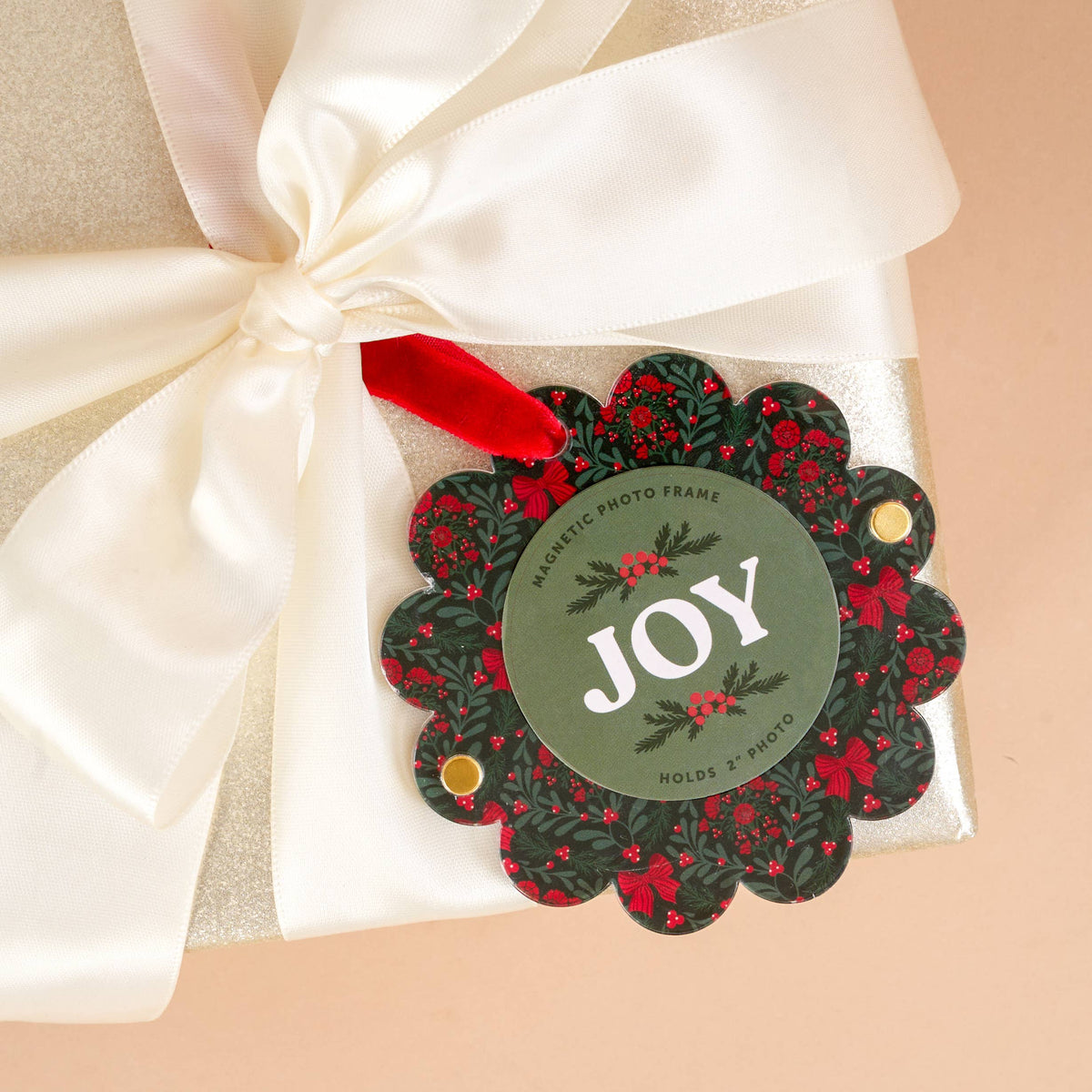 Scalloped round picture frame ornament with red ribbon, 'JOY' on dark green floral base