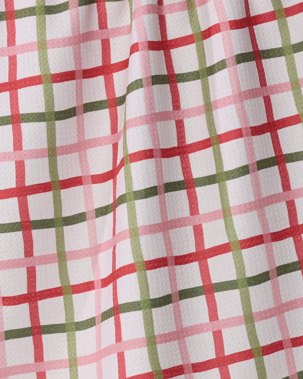 Plaid tea towel fabric close-up, red and green grid squares on white cloth