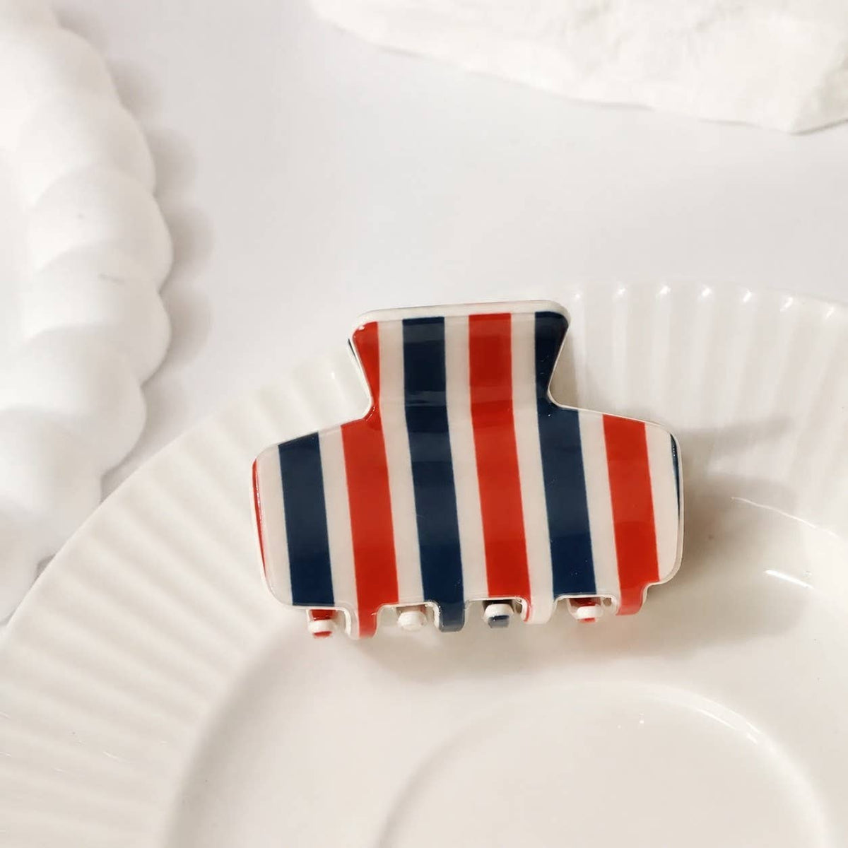 Striped hair claw clip with navy, red, and white vertical stripes