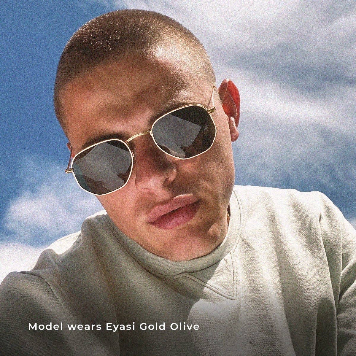 Gold-tone carbon sunglasses on a person, dark lenses with metal bridge