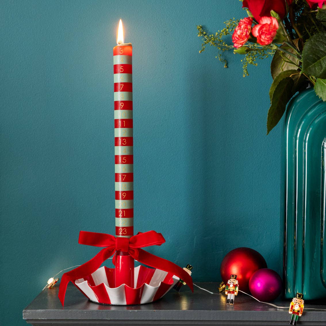 Red velvet ribbon bow with long streamers attached to a candle stand