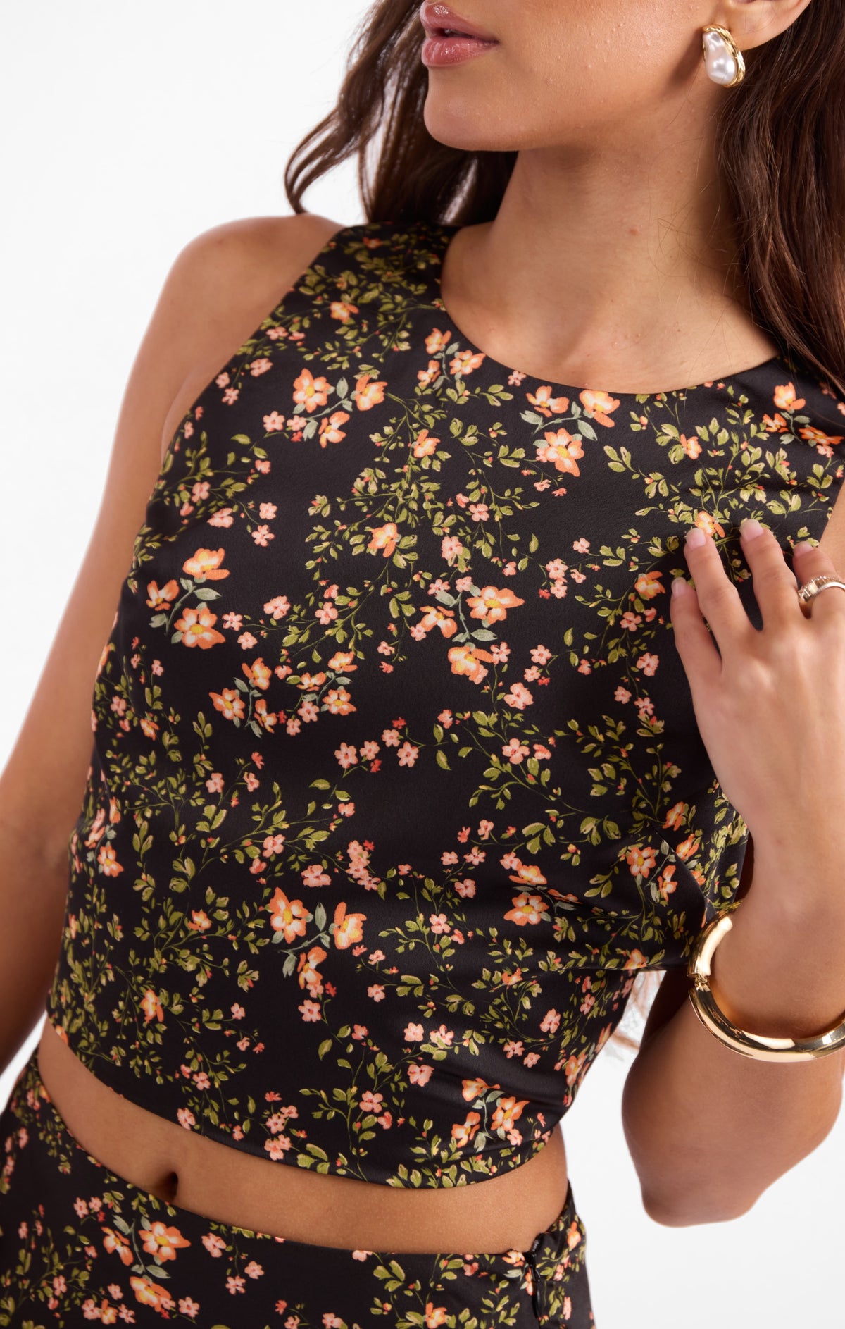 Floral sleeveless top close-up with crew neckline and gathered hem, black with orange blooms