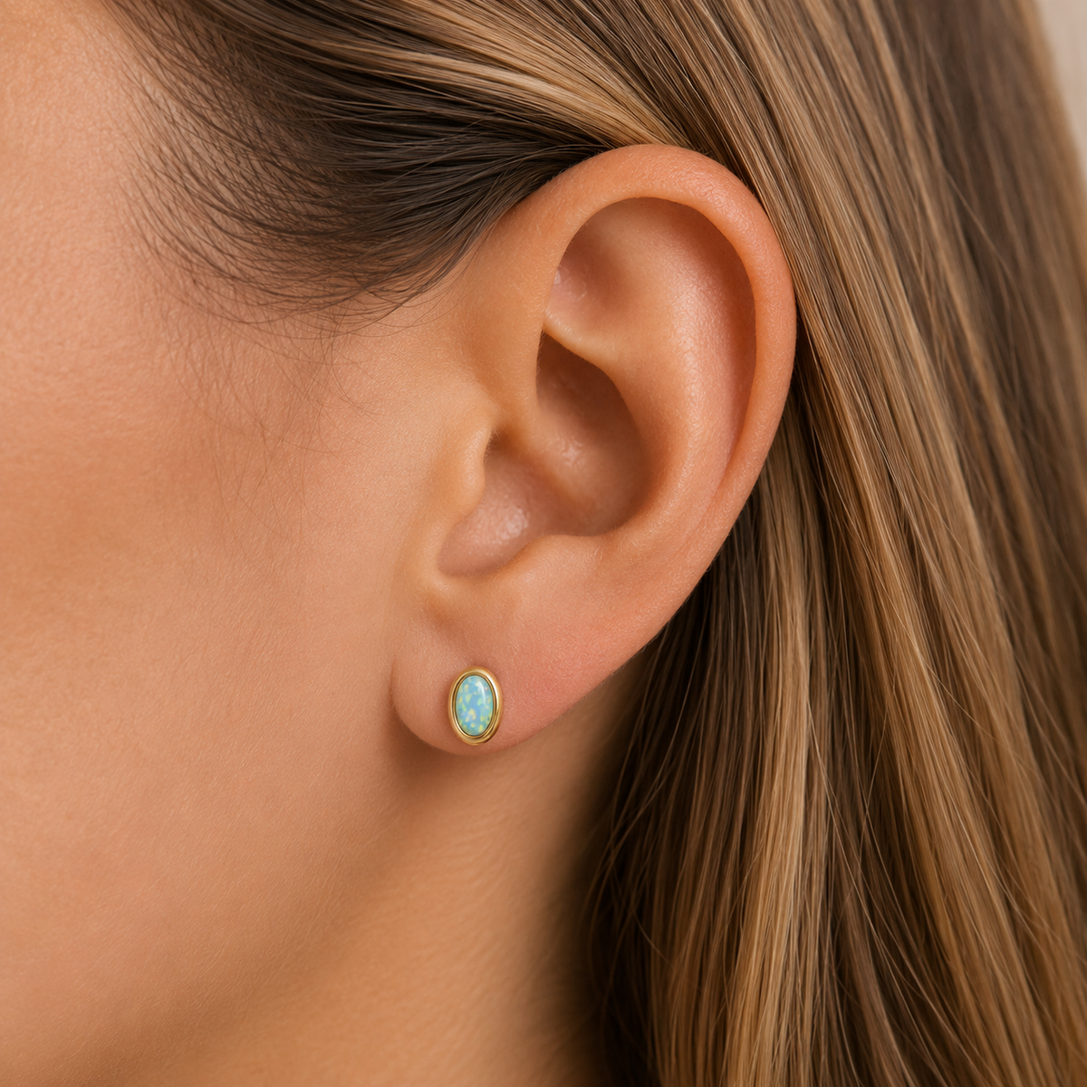 Single oval bezel opal stud earring with gold-tone setting and turquoise center