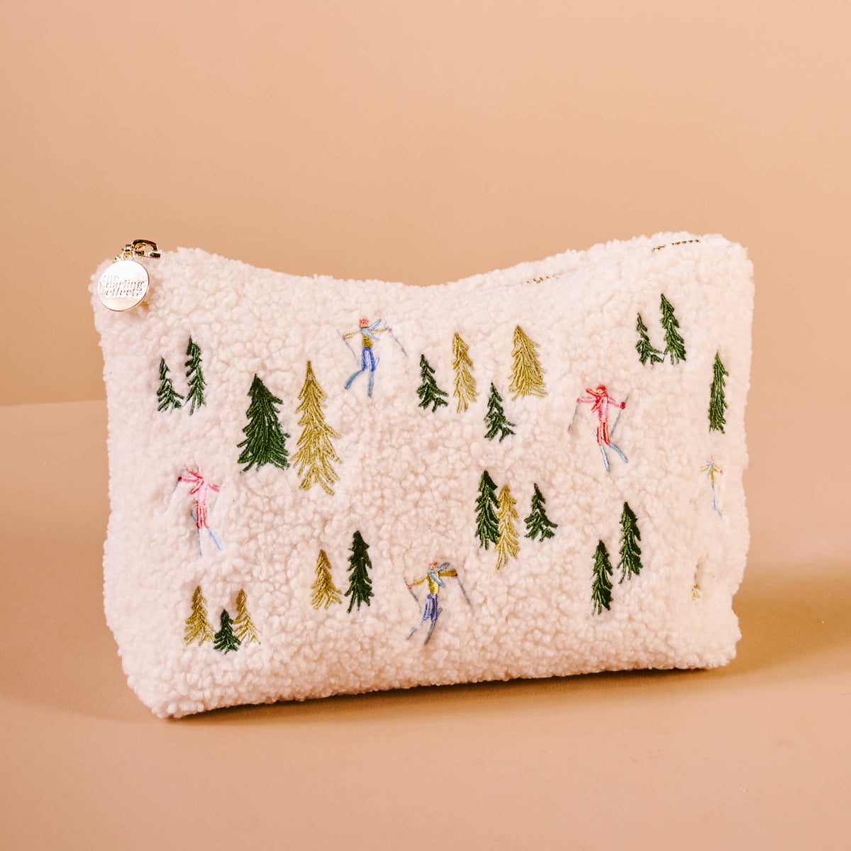 White teddy pouch with embroidered pine trees and small ski figures, zip top