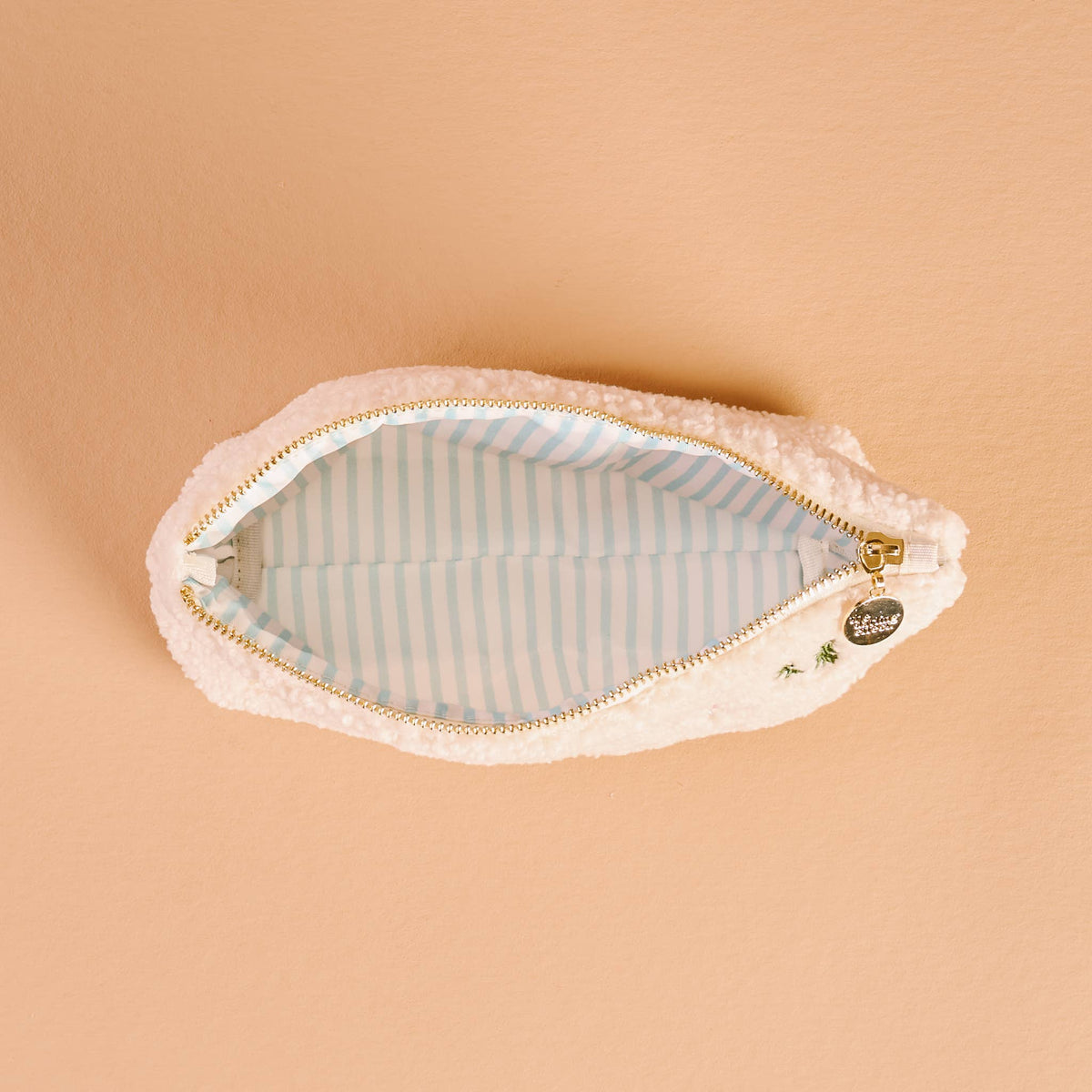 Teddy pouch with striped blue lining and gold zipper, viewed open