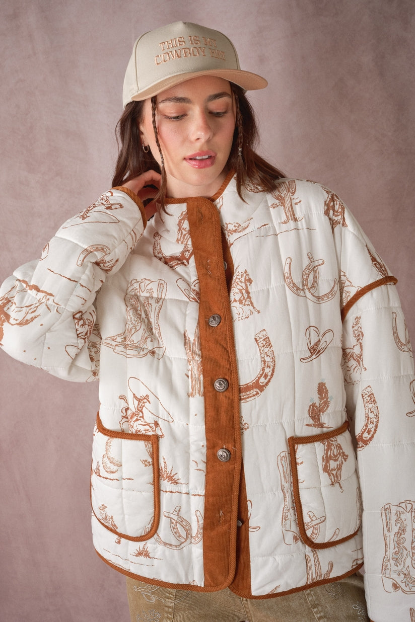 Western quilted jacket front detail, white with cowboy print, brown cord trim and snap buttons