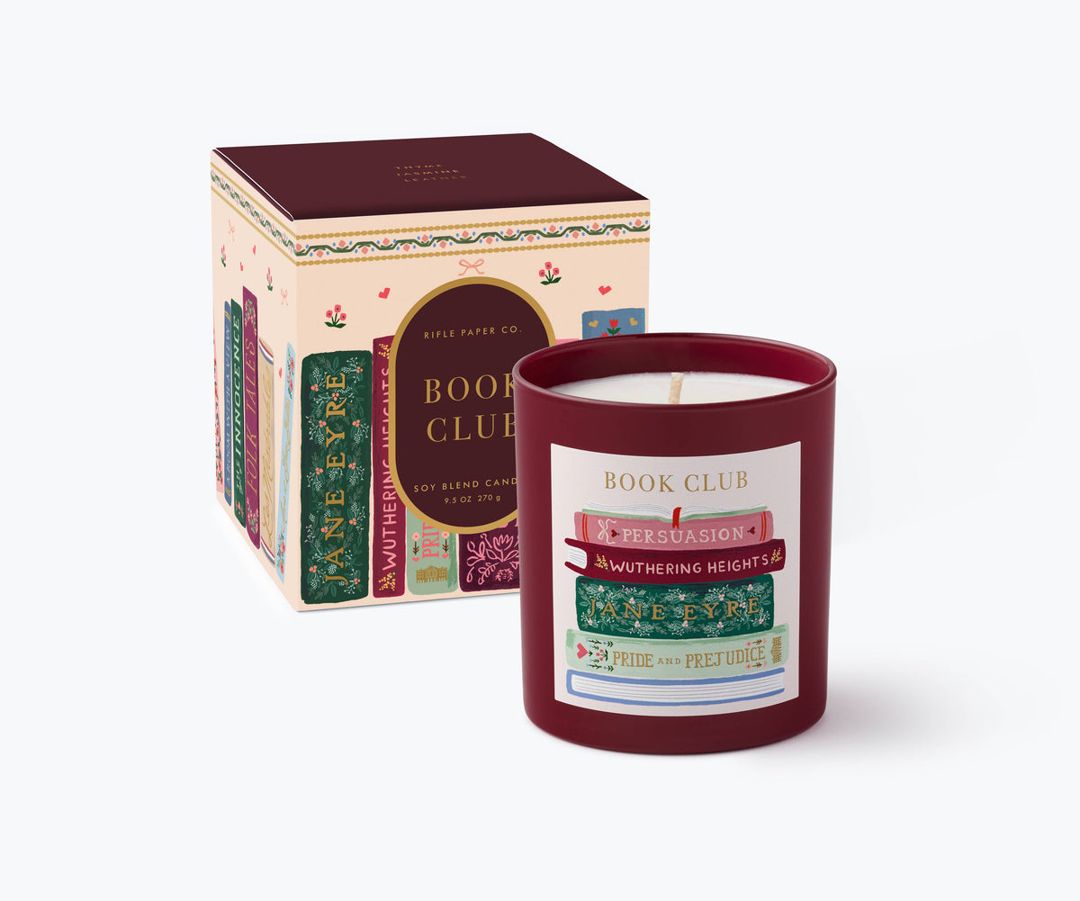 Burgundy glass candle in front of boxed Book Club candle packaging