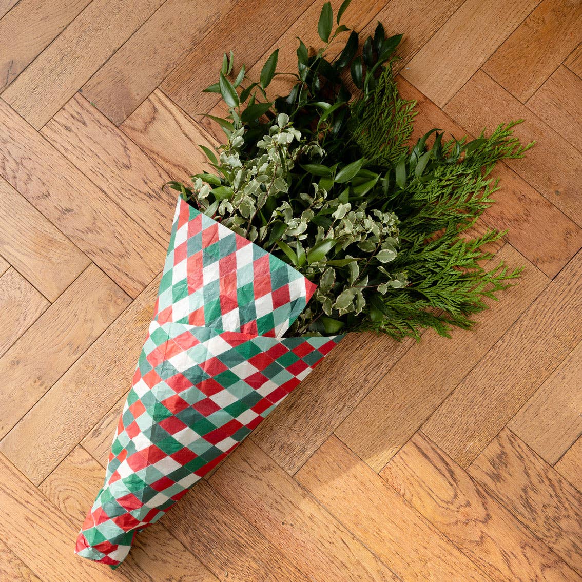 Folded tissue paper sheet with red, green, and white diamond pattern on floor