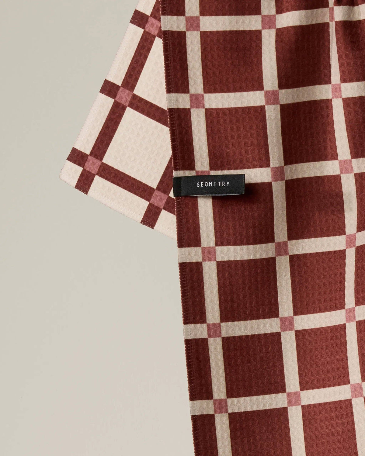 Red and white checkered kitchen towel with waffle texture and black label