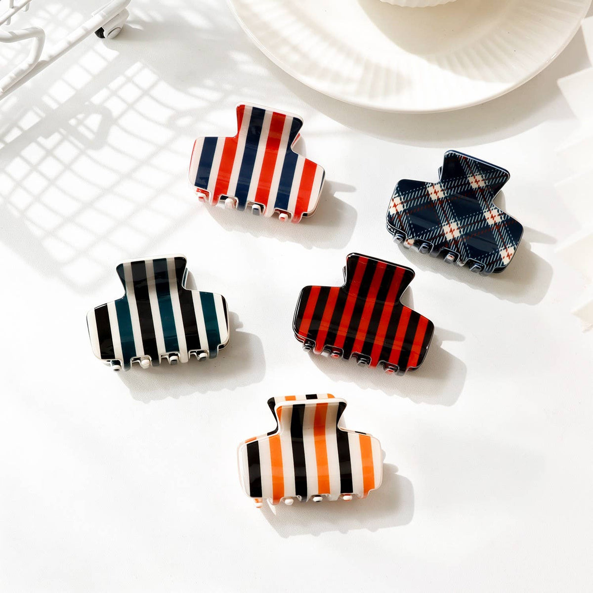 Assorted striped and plaid hair claw clips arranged on white plate