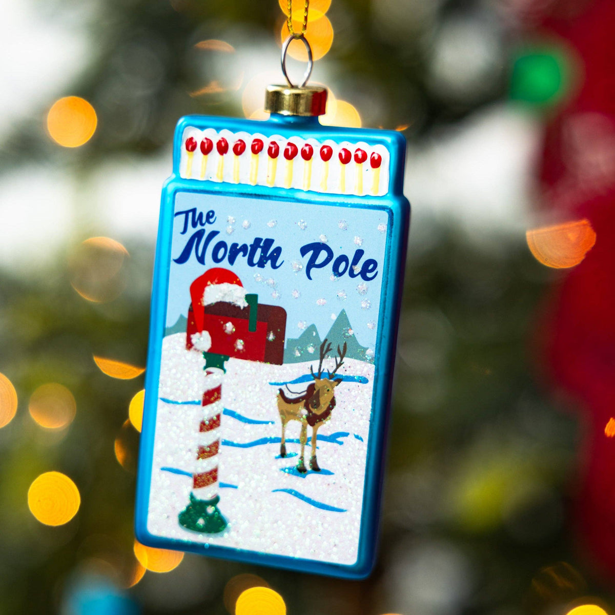 Blue matchbook ornament with "The North Pole" and snowy Santa scene
