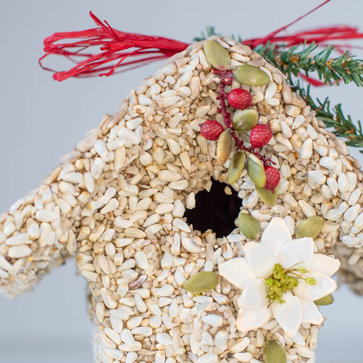 Seed birdie cottage ornament with white flowers, green leaves, red berries, and red hanger ribbon