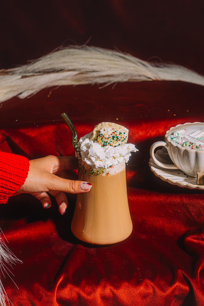 Single latte in glass with whipped cream and sprinkle cookie topper