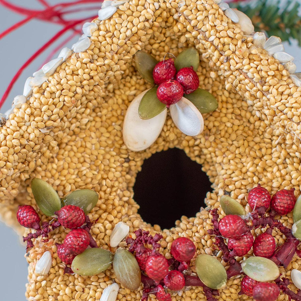 Seed birdie cottage ornament with central white flowers, red berries, and green leaf trim