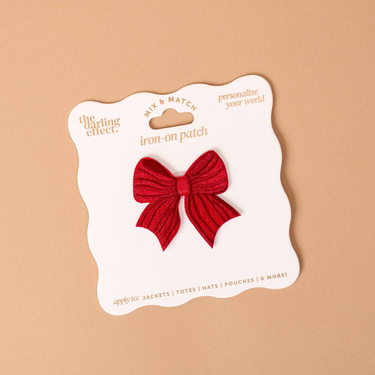 Red bow iron-on patch on white card backing, scalloped edges