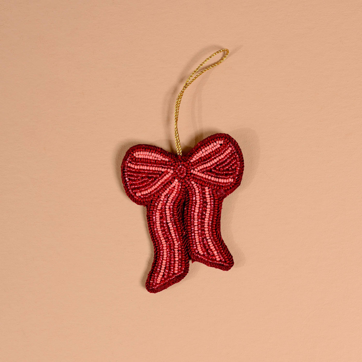 Red beaded bow ornament with gold cord, angled view