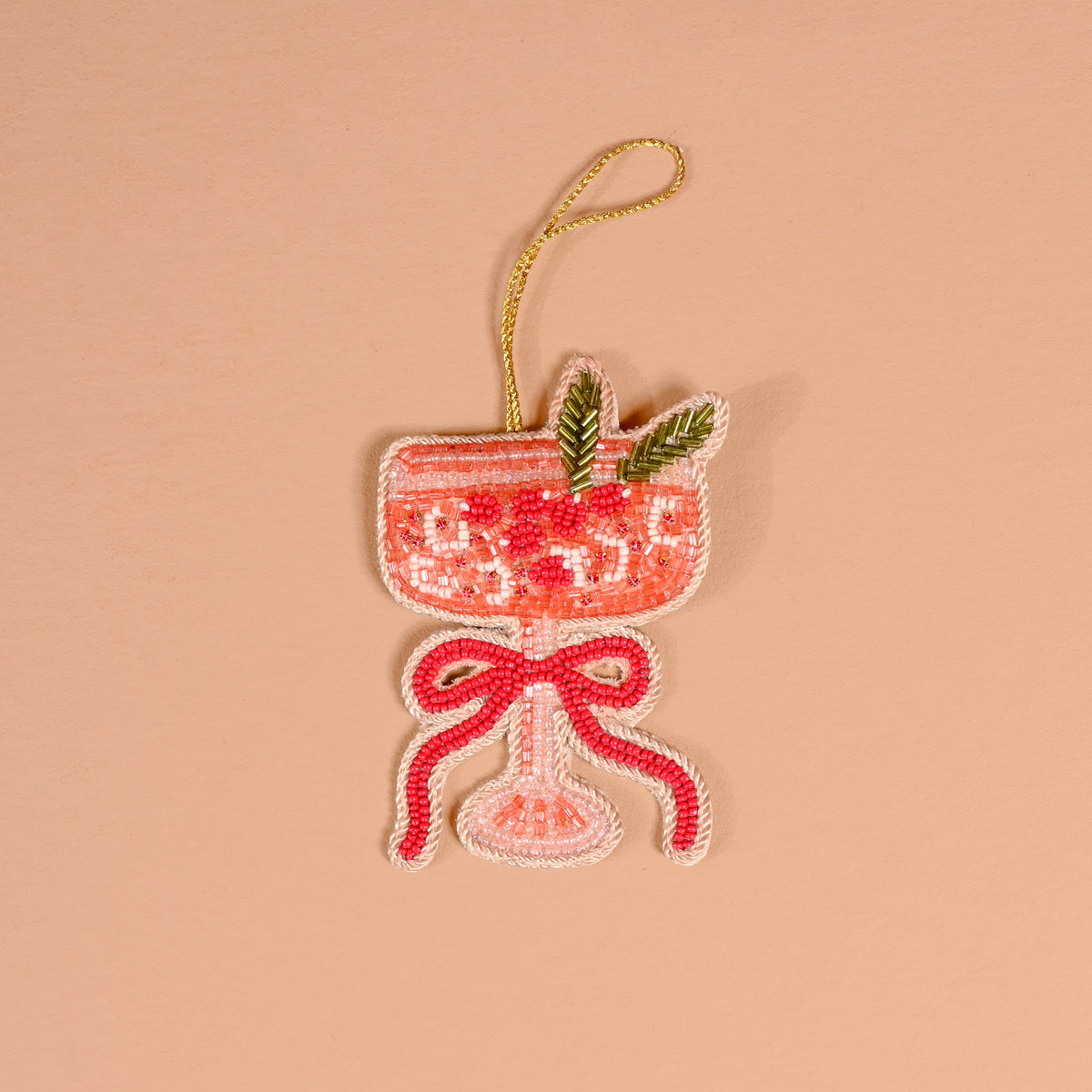 Red beaded ornament with bow and green leaf accents, hanging from a gold cord loop