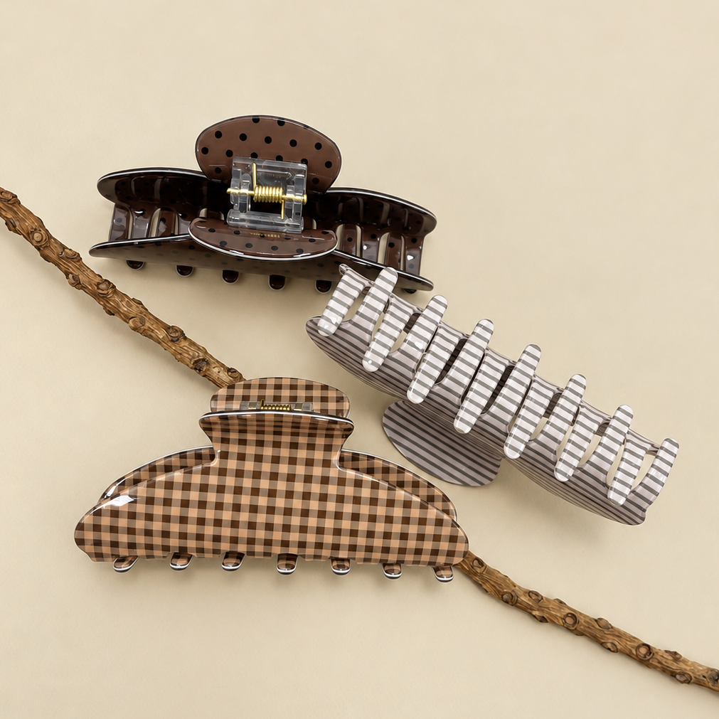Jumbo oval hair claw clips featuring dark polka-dot, gray stripe, and brown plaid.