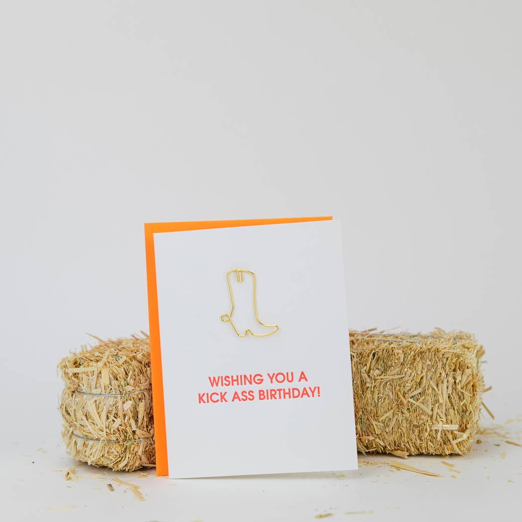 Birthday letterpress card with gold boot icon and red message, orange envelope edge visible.