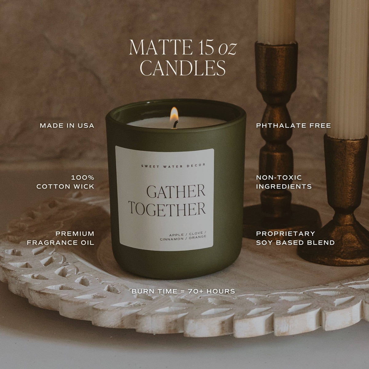 Olive green soy candle jar with lit wick on a decorative stone-like base