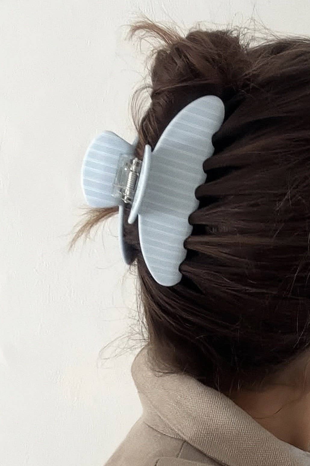 Light blue striped oval jumbo hair claw clip on hair, with metal hinge hardware.