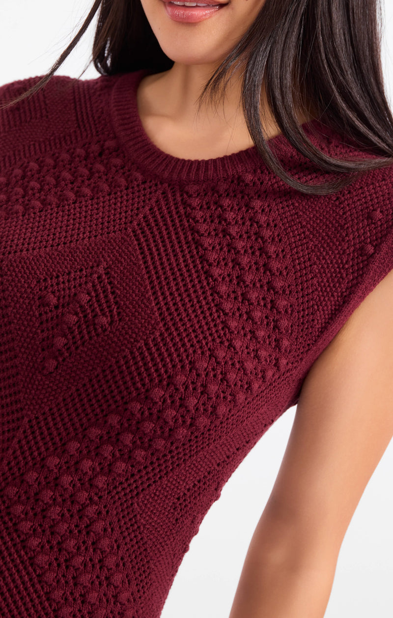 Intricate knit dress close-up, dark maroon sleeveless crewneck textured pattern