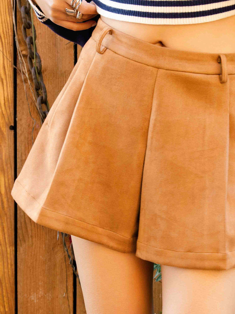 Tan faux suede shorts close-up: pleated front, belt loops, button-and-zip closure