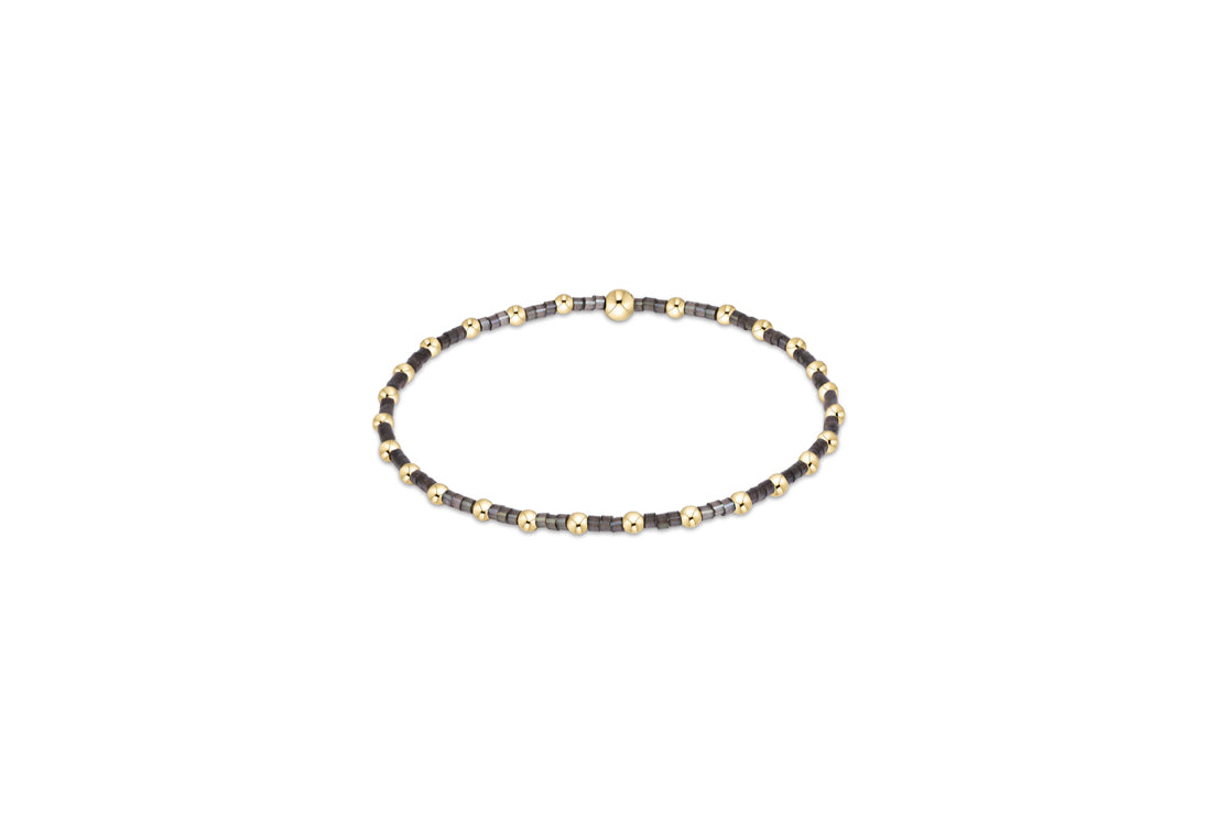 Beaded bracelet with dark beads and light spacer beads on gold-tone chain