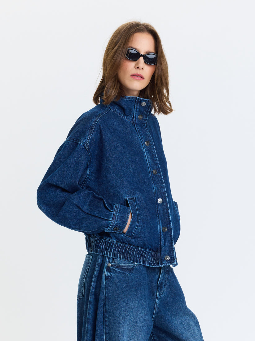 Blue denim funnel-neck jacket with snap front, front pockets, elastic cuffs