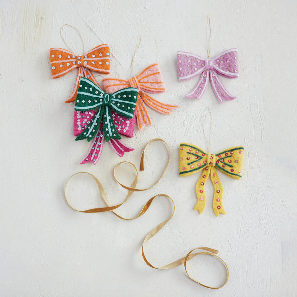 Felt bow ornaments with ribbon tails and loops in orange, green, purple, and yellow.