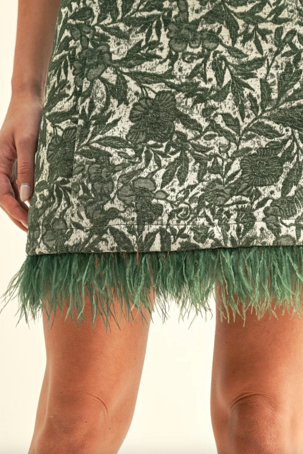 Close-up: green leaf print dress hem with teal faux feather fringe