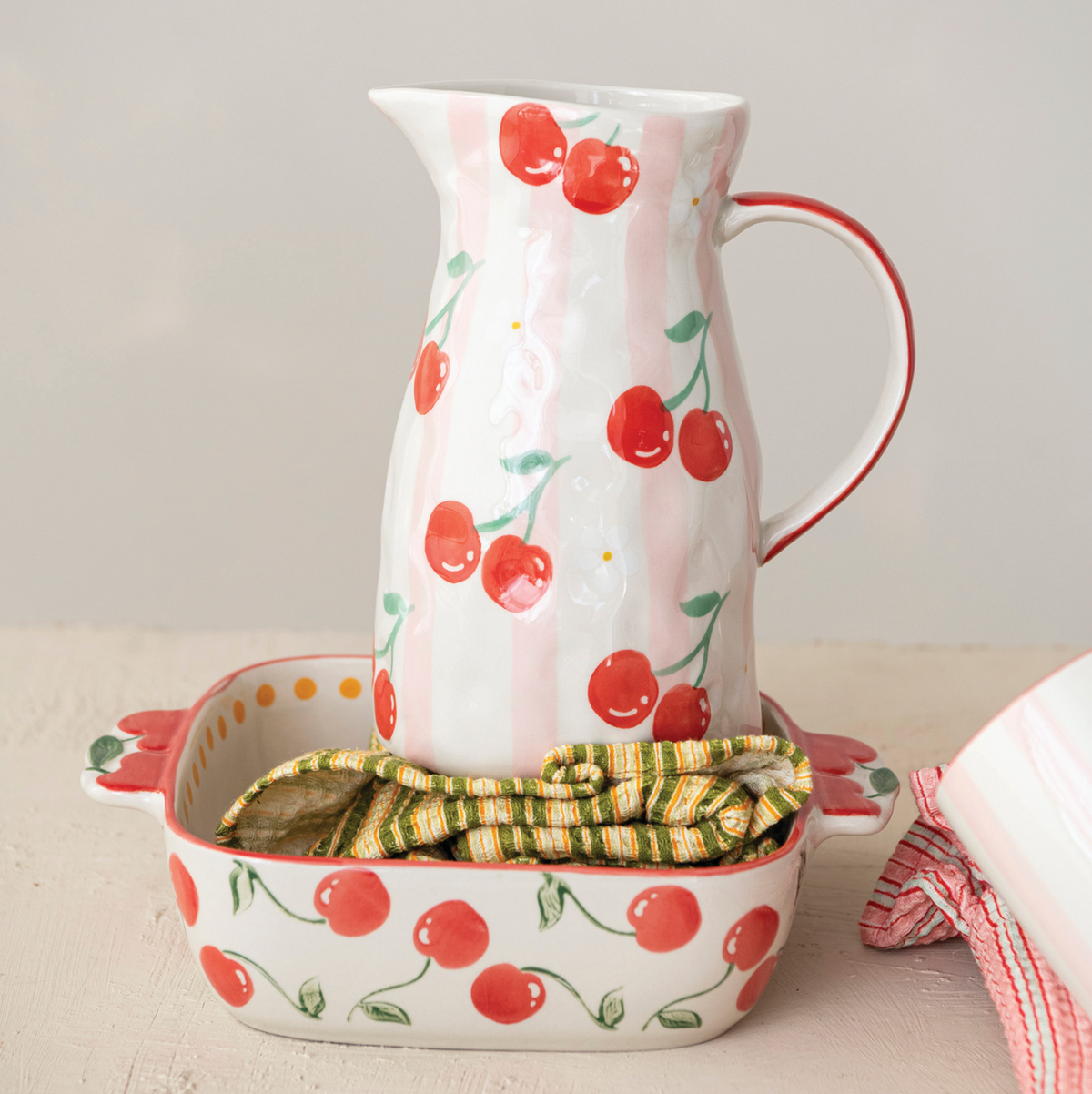 Cherry-pattern stoneware baking vessel with curved handle, spout, and leaf accents