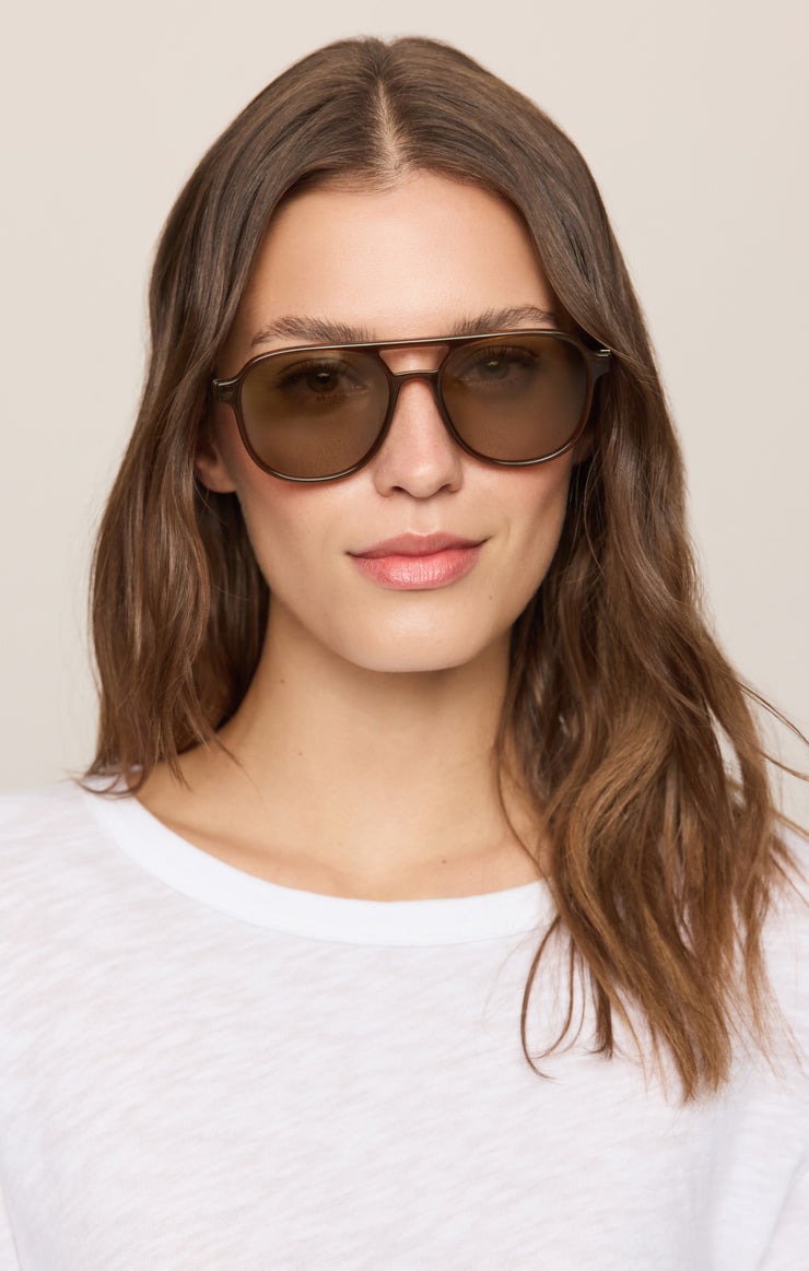 Woman wearing brown polarized sunglasses with round lenses and thin metal arms