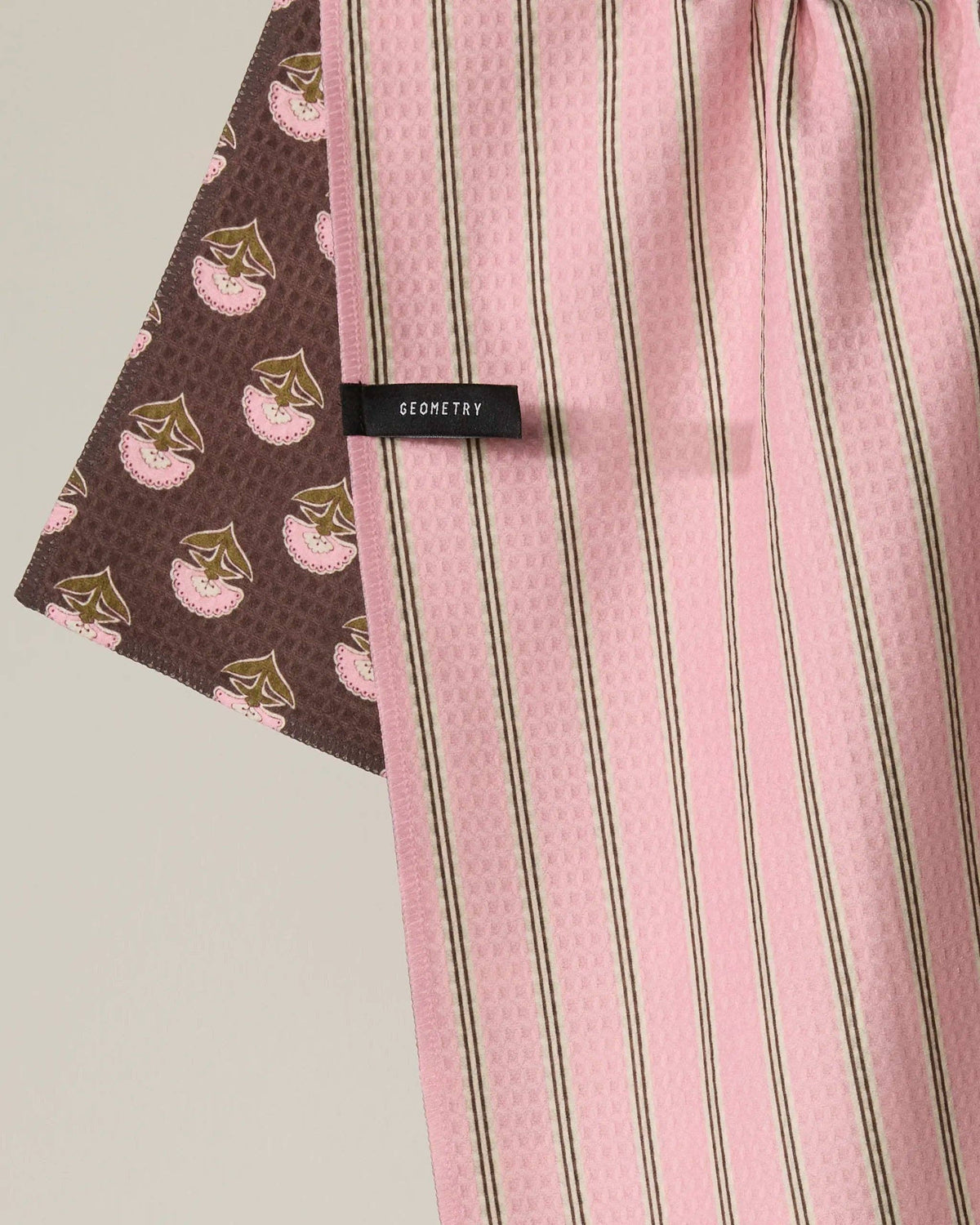 Kitchen towel with pink vertical stripes and brown floral border, fabric close-up
